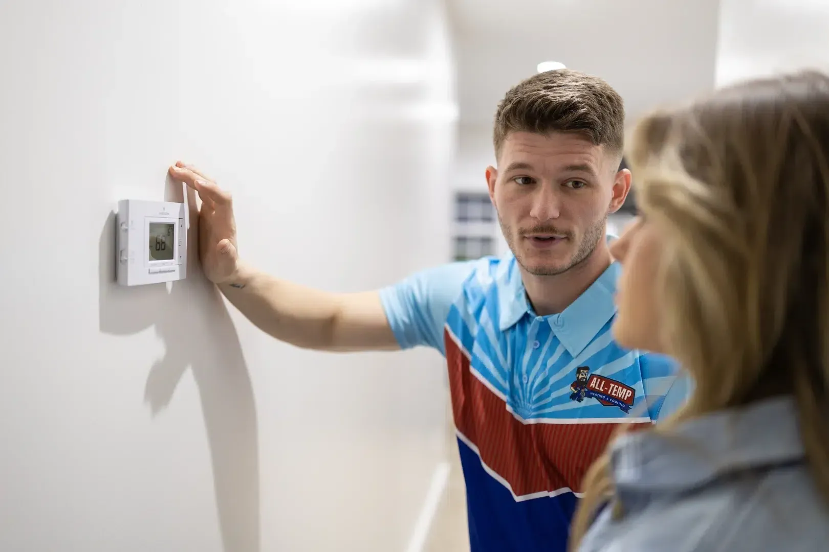 Harrisonburg thermostat repair service technician adjusting modern home thermostat