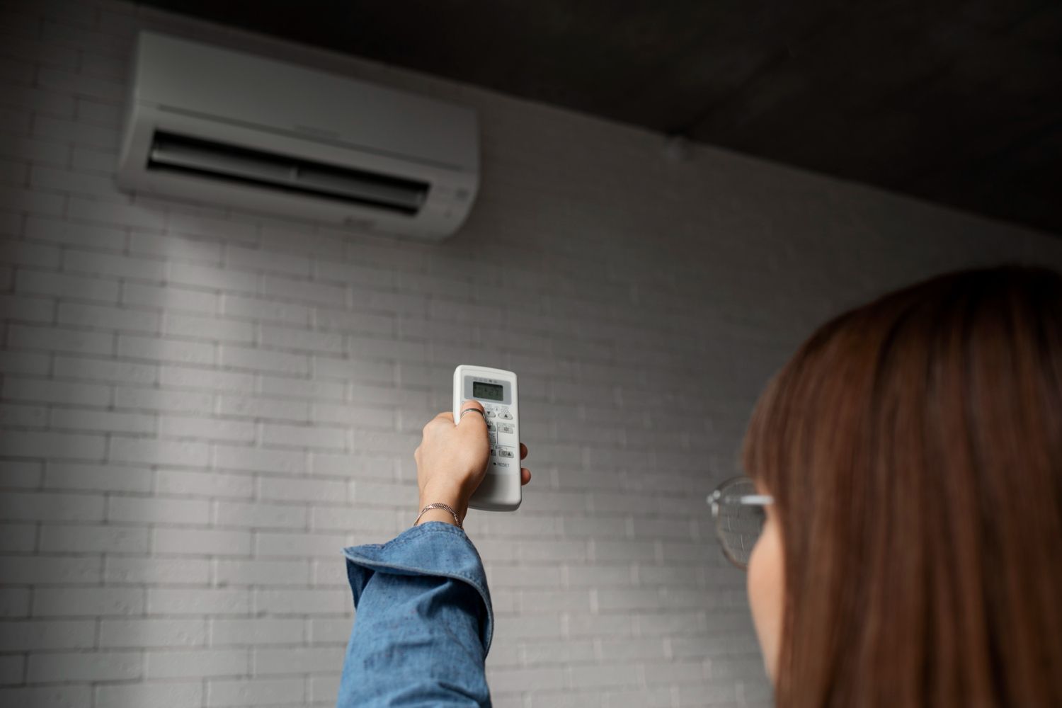 Woman controlling wall air conditioner