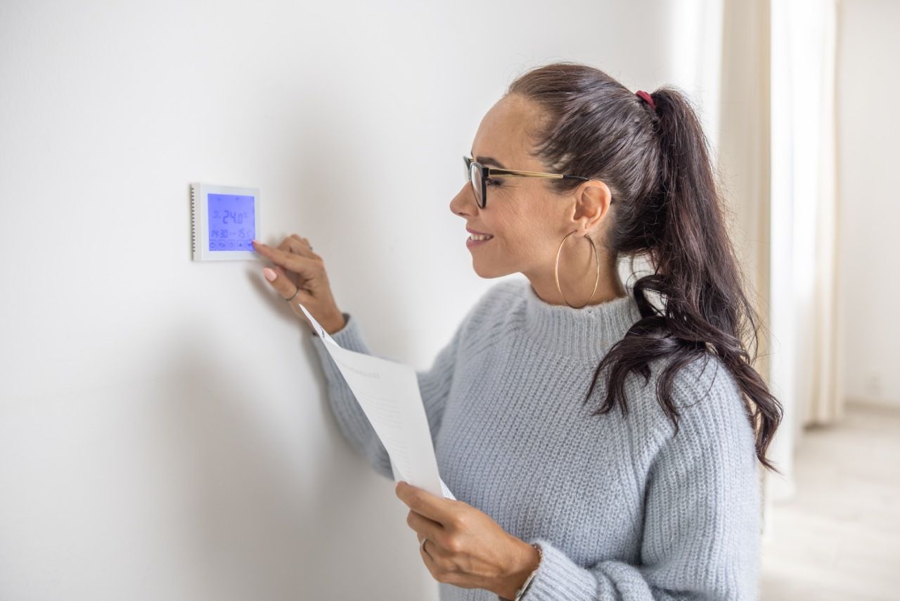 Woman using home thermostat control