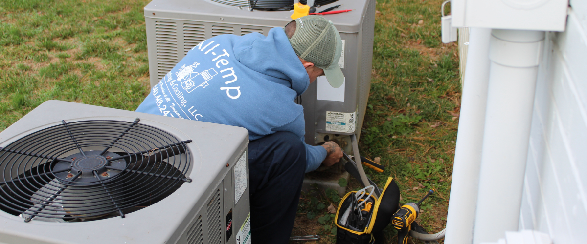 All Temp technician performing maintenance on an outdoor unit